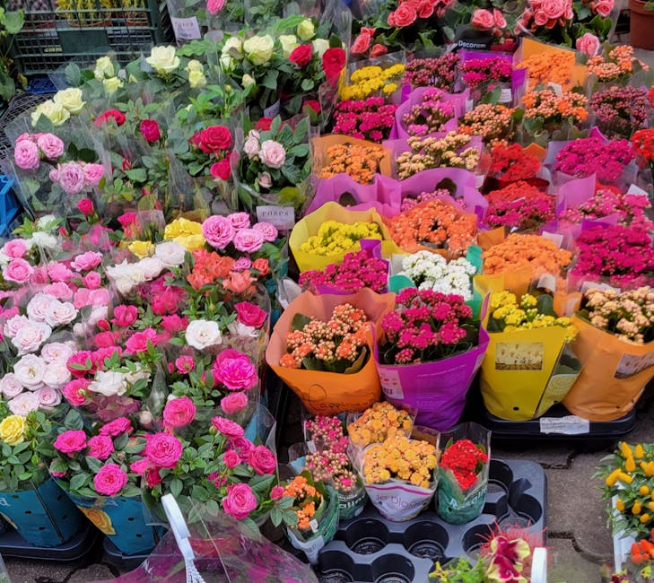 A vibrant display of fresh floral arrangements at a flower stall, featuring an array of roses in shades of pink, white, and yellow, alongside smaller bouquets of brightly colored chrysanthemums and st